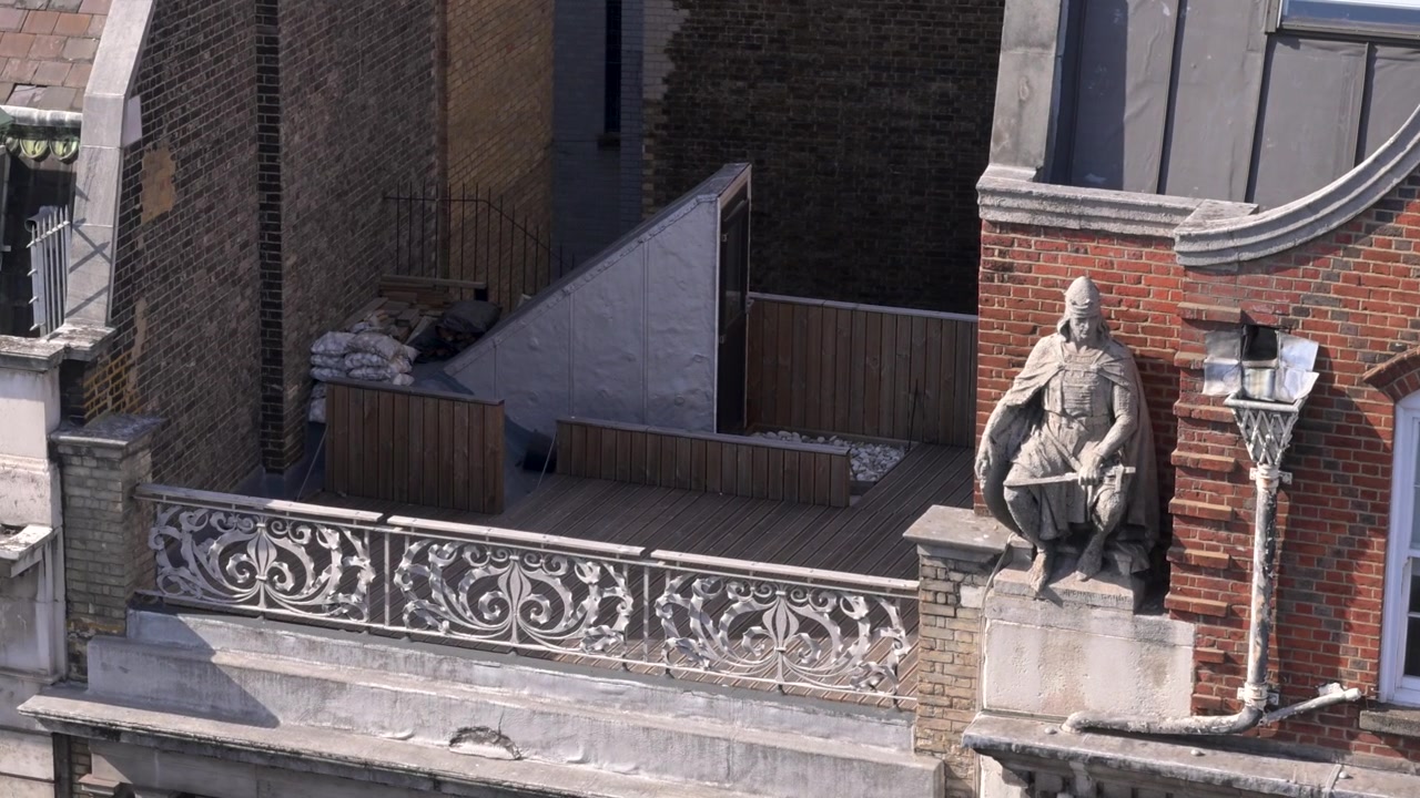 La statua di Richard Garbe si trova sulla facciata ornata e sulla terrazza panoramica di Kingsgate House a High Holborn, Londra, vista da un'angolazione elevata in una giornata di sole