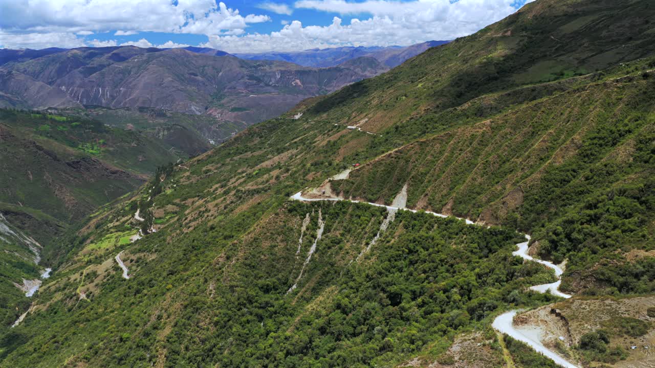 Car driving windy dirt road dust Soray Laguna Lake Humantay Sulcantay Trek Peru Perú aerial drone clouds blue skies high altitude elevation Peruvian Andes Mountain Range peaks forward follow motion