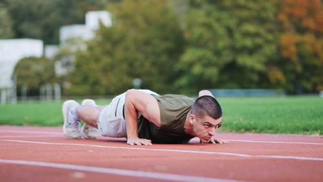 joven atlético que se entrena en flexiones en la pista de rattling de una instalación deportiva