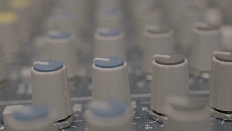 un primerísimo plano de las perillas del mezclador de audio en el estudio de grabación