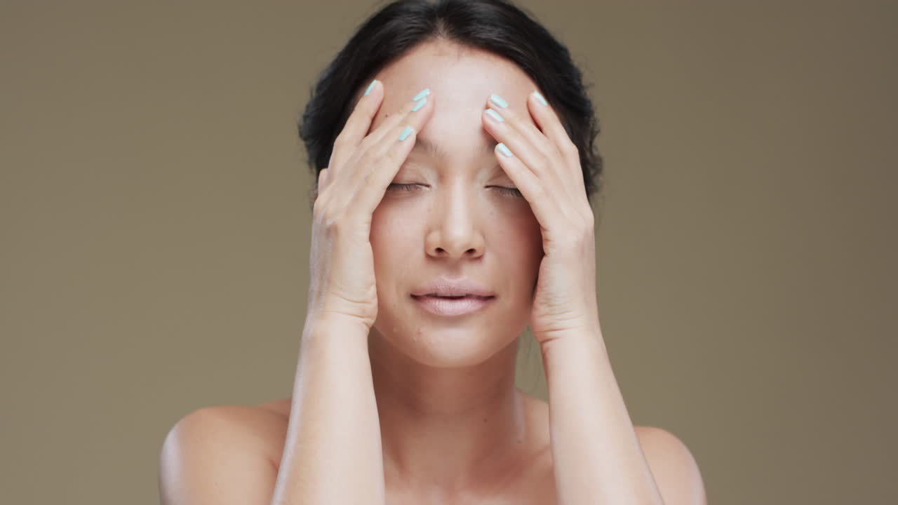 베이지색 배경에 어두운 머리카락을 가진 행복한 아시아 여성, 슬로우 모션