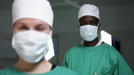 portrait of diverse surgeons wearing surgical gowns in operating theatre, slow motion