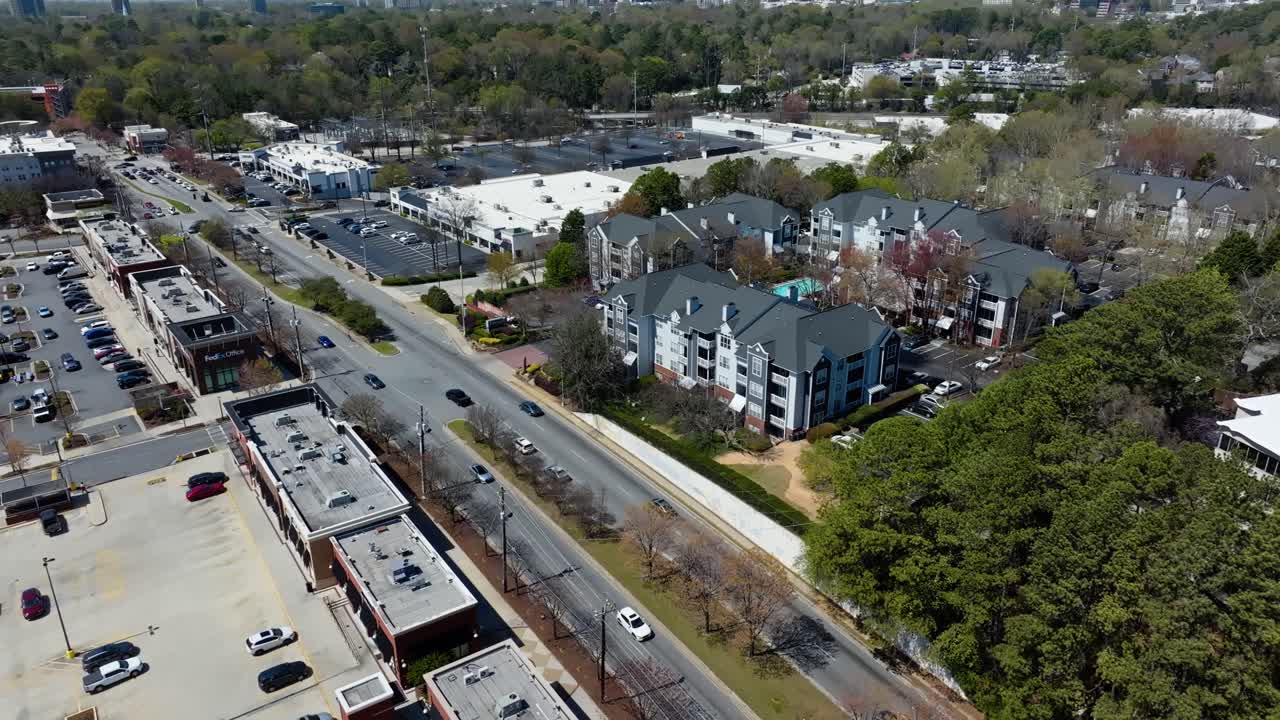 Aerial view of shopping center, parking cars, traffic on road and modern hotel apartments with swimming pool. Atlanta Suburb district in spring.