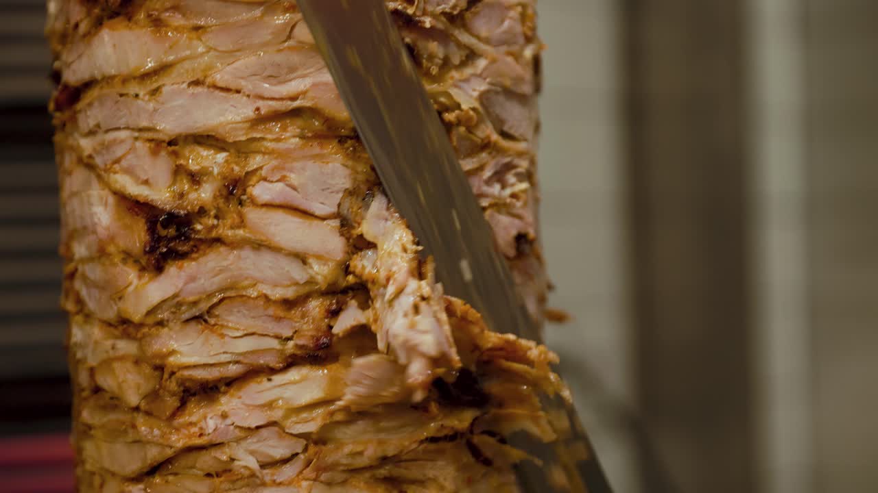 Close-up of a chef slicing meat off a rotating doner kebab, perfect for street food, restaurant, and culinary preparation visuals