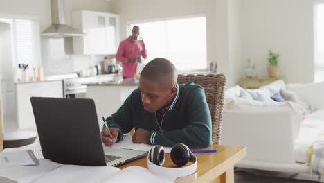 video de un niño afroamericano enfocado con una computadora portátil teniendo lecciones en línea en casa