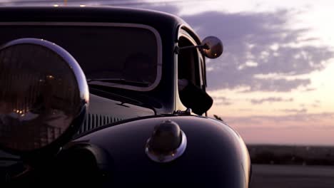 primer plano de un coche antiguo único, conductor esperando a la novia y al novio al atardecer de la boda