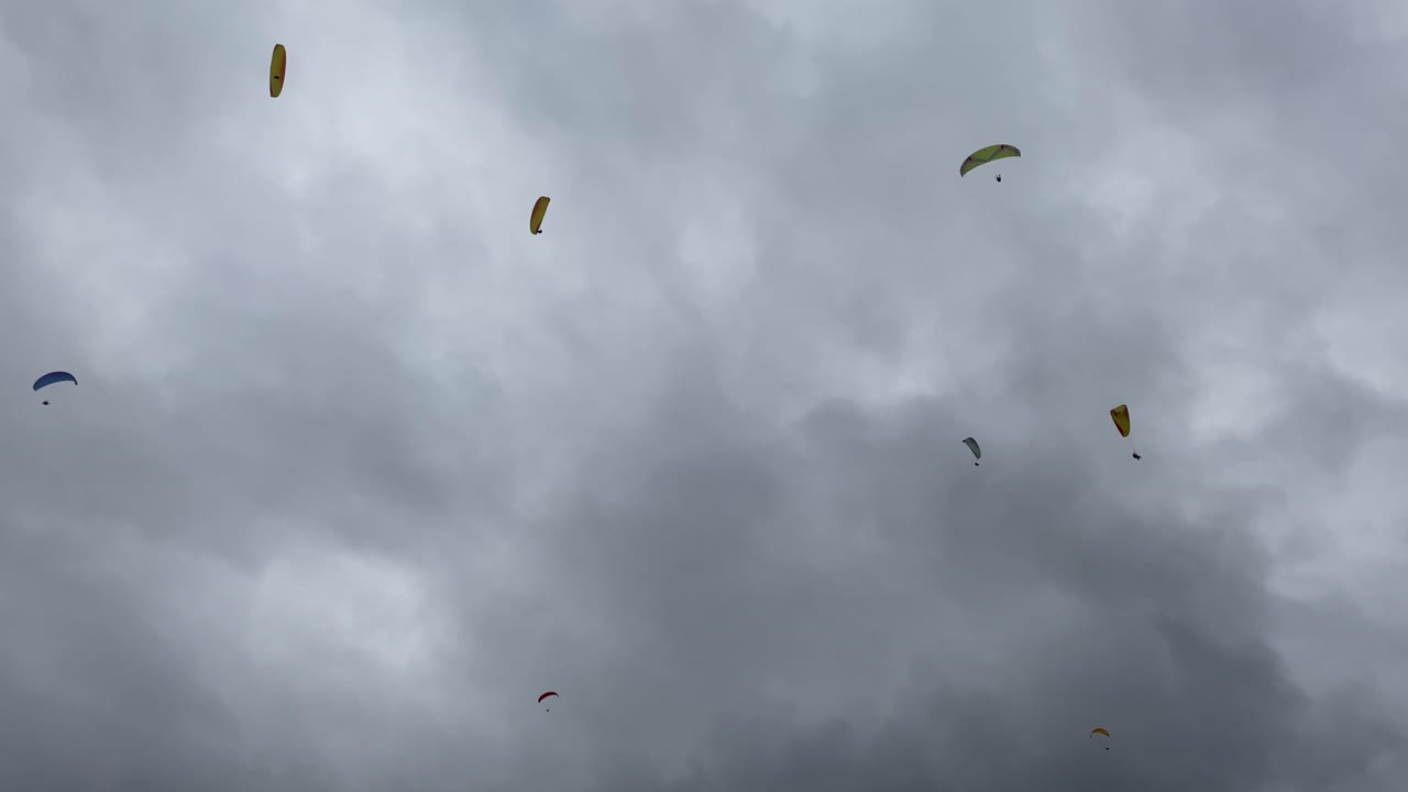 Group of people gliding competition, spectacular flight high in cloudy sky