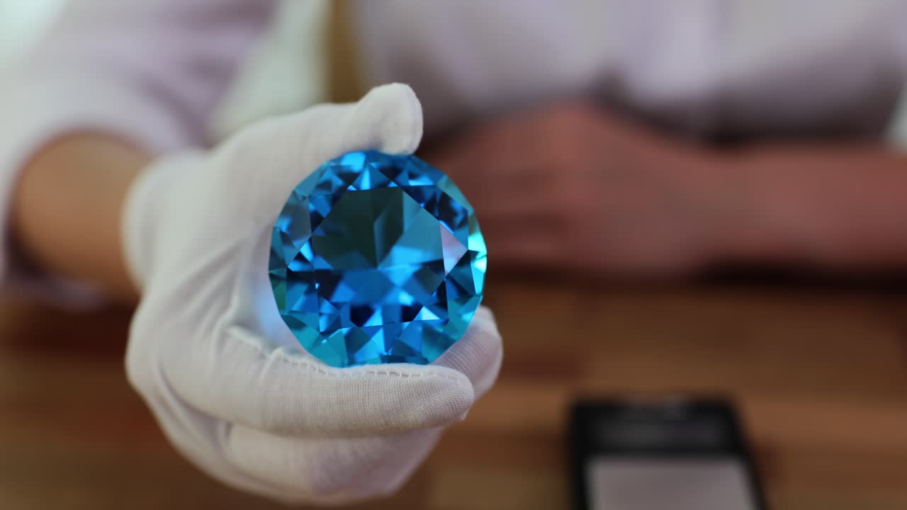 Gloved Hand Holding a Large Blue Gemstone