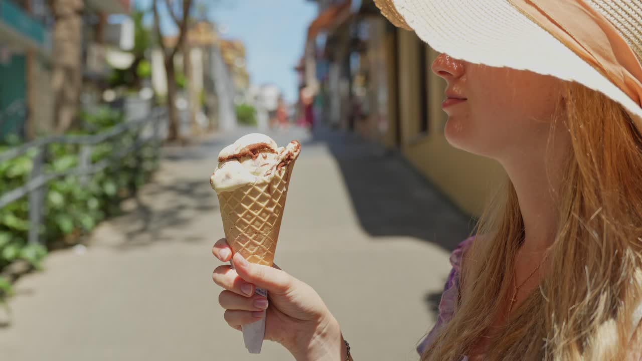 Bionda felice si gusta un delizioso gelato a Puerto de la Cruz, vista laterale.
