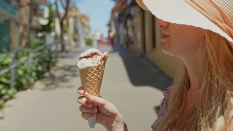 happy blonde enjoys delicious ice cream in puerto de la cruz, side view