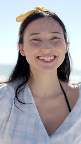 vertical video: smiling woman enjoying sunny day at beach, wearing casual summer outfit