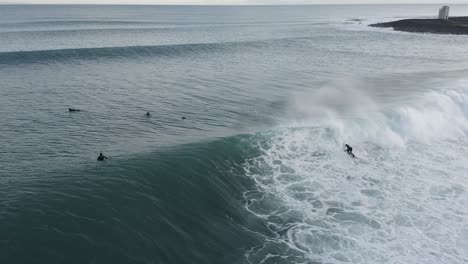 Epic-slow-motion-shot-of-surfer-riding-wave-in-cold-Iceland-water,-aerial