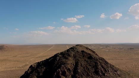 cima de una montaña rocosa en el vasto paisaje de la llanura del desierto de mojave, tirón aéreo