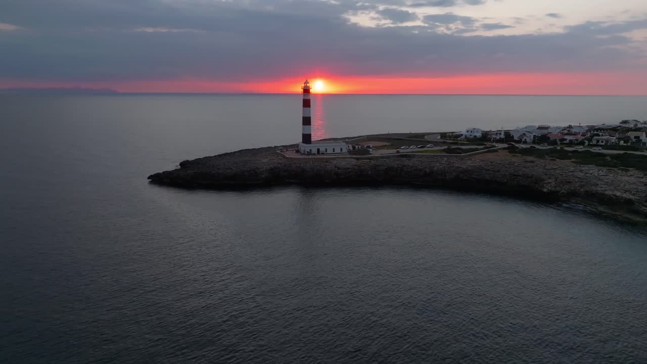 Aerial panoramic drone fly Menorca Coastline with Lighthouse at Sunset, fire sun glowing