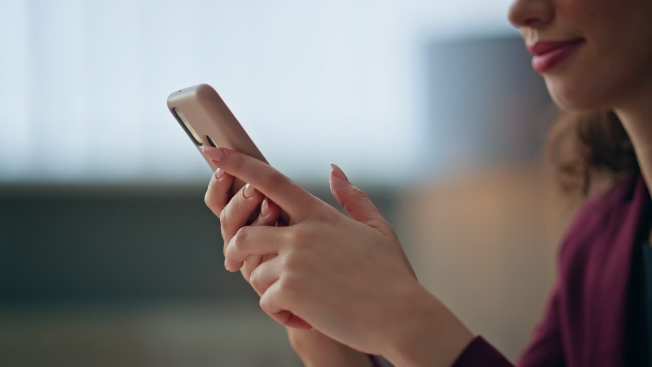 Primo piano di una donna d'affari che tiene in mano un telefono cellulare mentre si riposa in ufficio. Mani che utilizzano il cellulare.