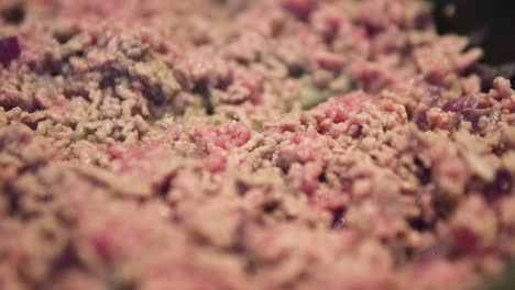 red and brown minced meat cooking in pan close up