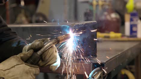 man mig welding metal bracket in machine shop