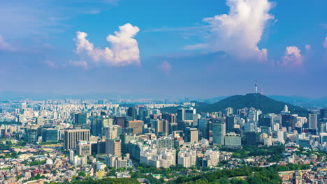 time lapse of moving clounds above seoul city skyline with business downtown distict with many skyscraper and office buildings around namsan tower on summer day, south korea - zoom out