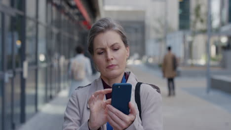 portrait-serious-mature-business-woman-using-smartphone-in-city-browsing-online-messges-texting-on-mobile-phone-slow-motion