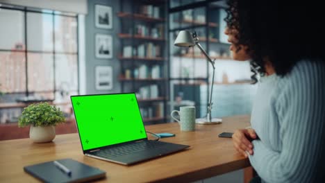 especialista femenina haciendo una llamada de video en una computadora portátil con pantalla verde en la sala de estar de la casa mientras está sentada en una mesa. freelancer hablando por internet en redes sociales.