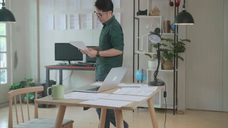 creative asian designer works on a storyboard, looks at his sketches and concepts, choosing the best drawings for his project. video editing, comics compilation, application ui or game plot