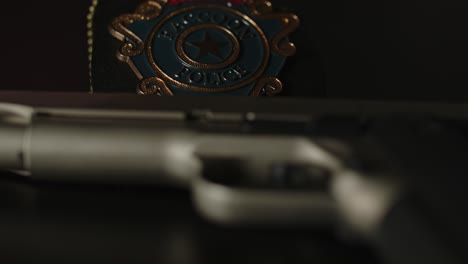 dolly in of pistol with a police badge in the background