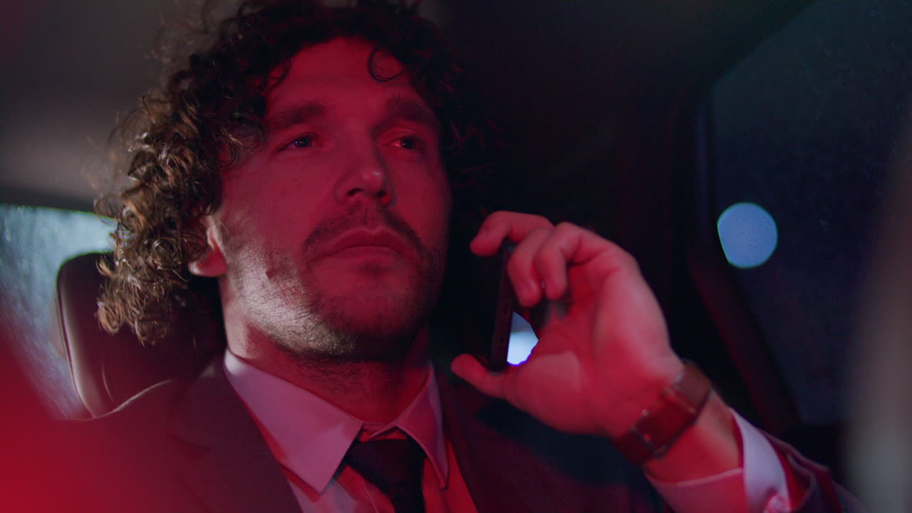 Young Businessman Talking on Phone in Taxi during Night Ride