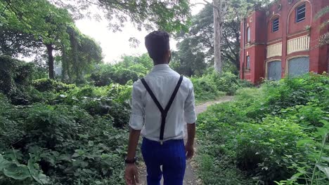 alone fashionable young male walk towards scary abandoned house in forest, slow motion