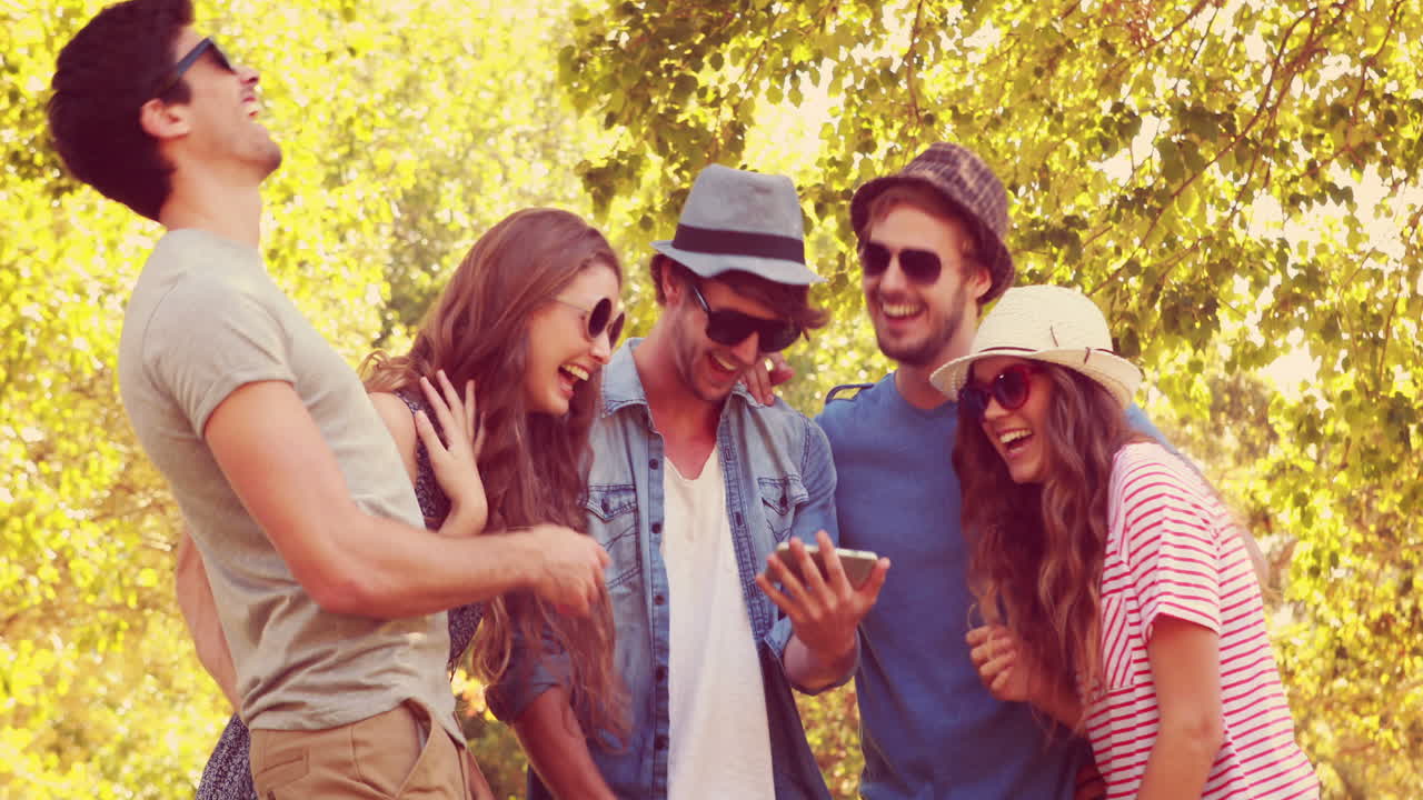 Amici felici che guardano foto su uno smartphone al parco