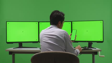 hombre trabajando en una computadora con monitores de pantalla verde