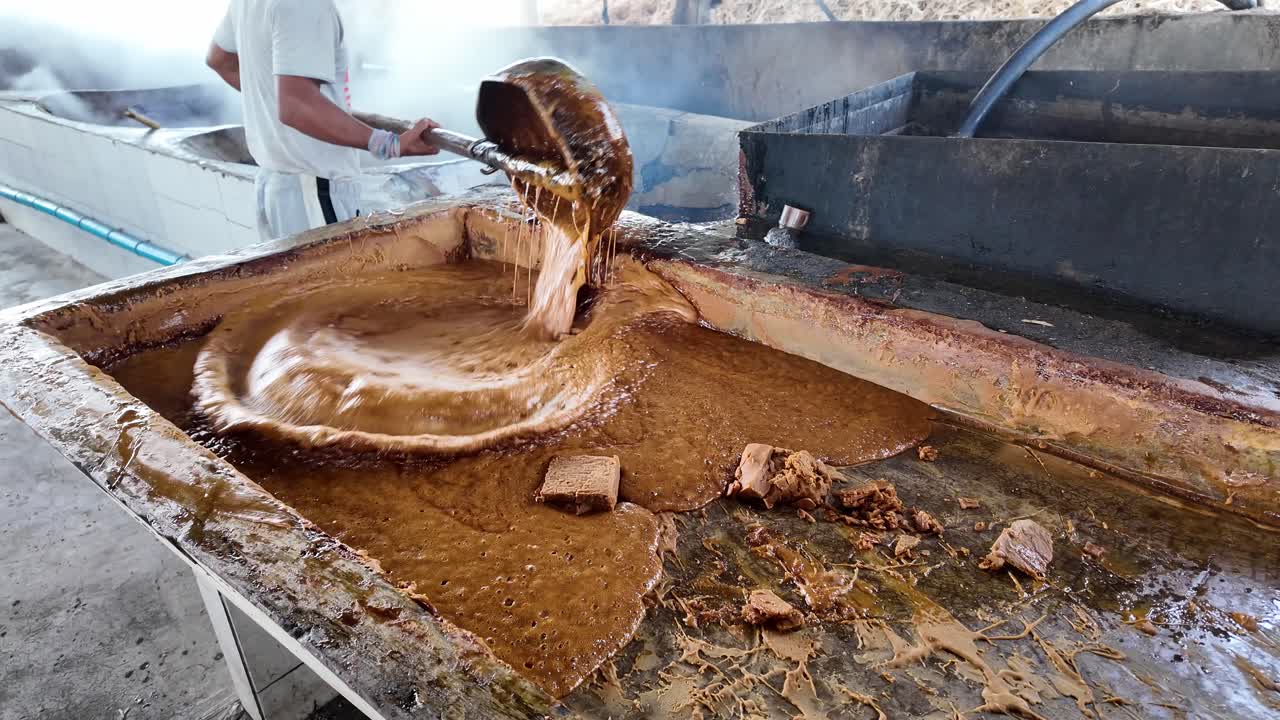 Man working with hot sugarcane juice during traditional brown sugar making
