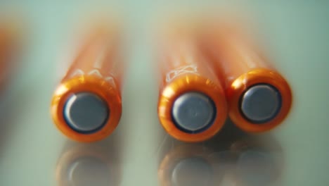 macro video of a pile of rolling batteries on a desk with reflection, golden battery, slow motion 120 fps