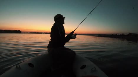 Vista-De-Una-Niña-Pescando-Desde-Un-Bote-Con-Una-Hermosa-Puesta-De-Sol-En-El-Fondo-En-Sudáfrica