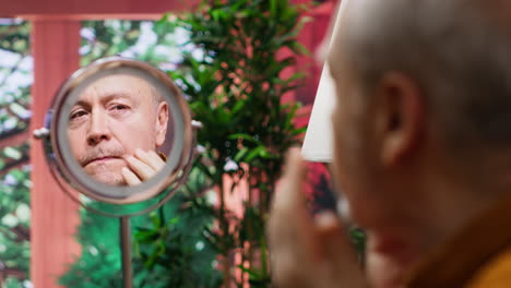 elderly man looking in the mirror at his wrinkles and aging skin