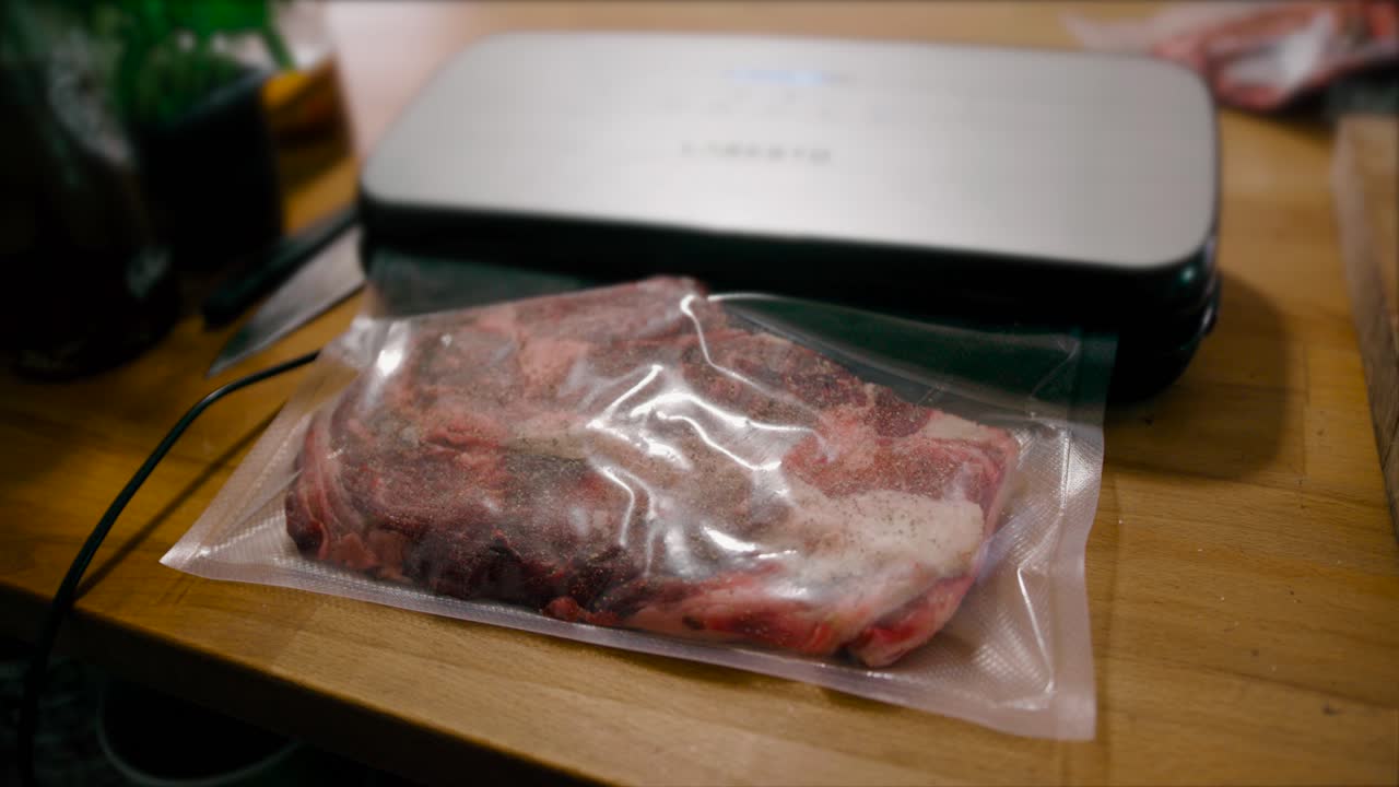 la confezionatrice sottovuoto avvolge la carne cruda in preparazione alla cottura sous-vide