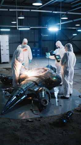 scientists in hazmat suits investigate and repair a crashed futuristic vehicle