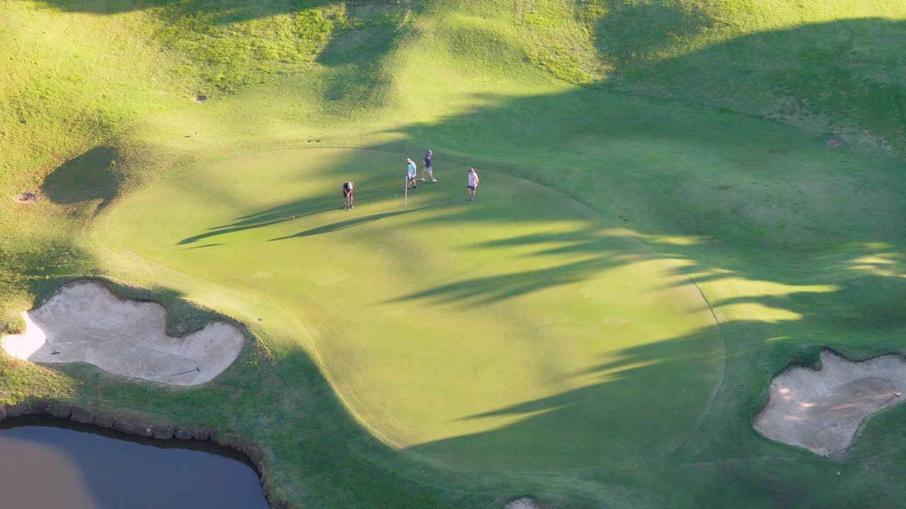 Golfers on a sunlit course in Gold Coast, Australia, captured by drone during golden hour, highlighting shadows and landscape