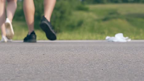 una joven pareja de patinadores camina en la vista trasera de la carretera gris