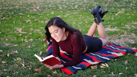 Una-Joven-Feliz-Leyendo-Un-Libro-De-Cuentos-Y-Sonriendo-En-El-Parque-En-Otoño
