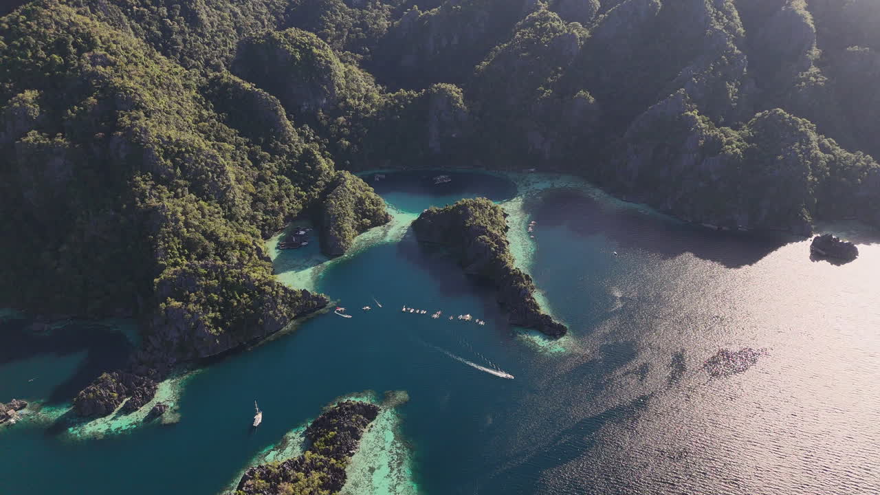Drone footage of Coron Island, Philippines, revealing its breathtaking beaches, lush vegetation, and towering rock formations. With a boat anchored in the water.