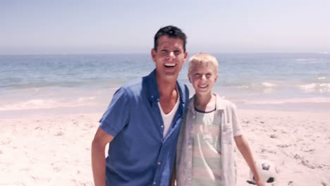 Happy-father-and-son-playing-football-on-the-sand