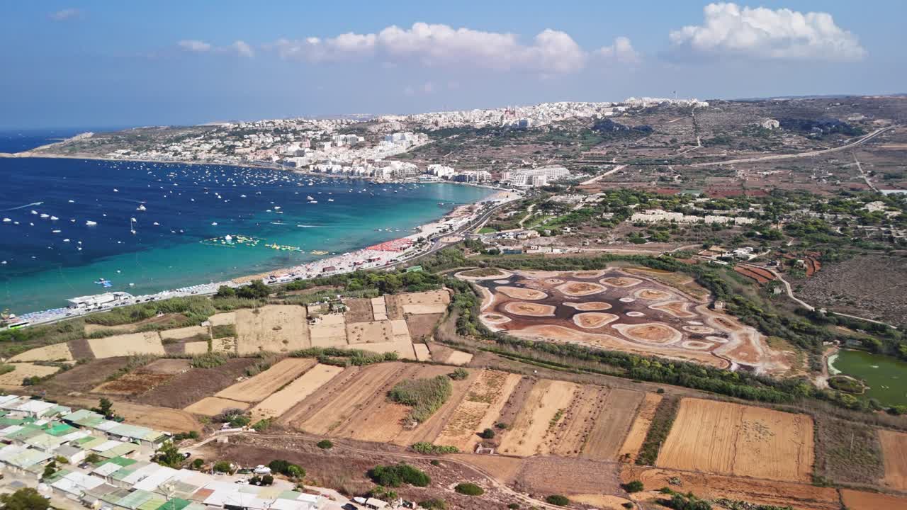 Aerial view of coastal cityscape with sea, fields, and blue sky