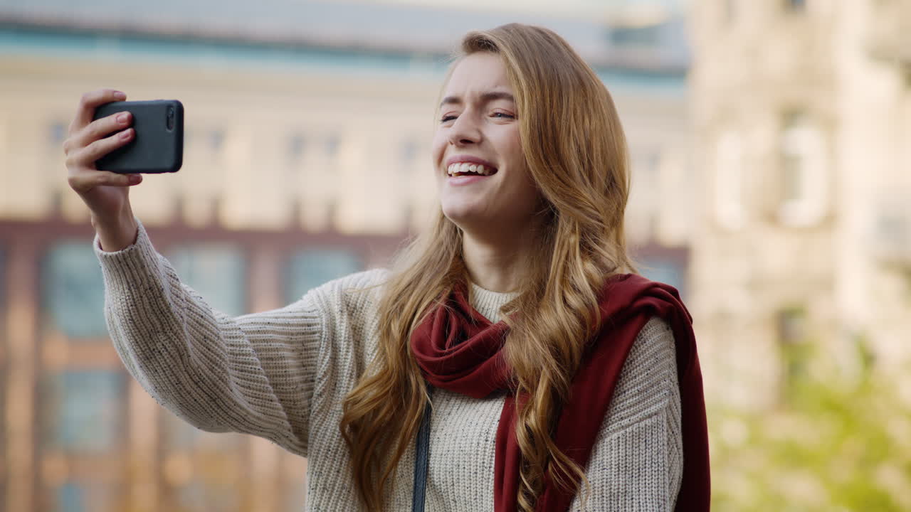 una chica feliz haciendo caras con el teléfono al aire libre. una mujer riendo sosteniendo un celular.