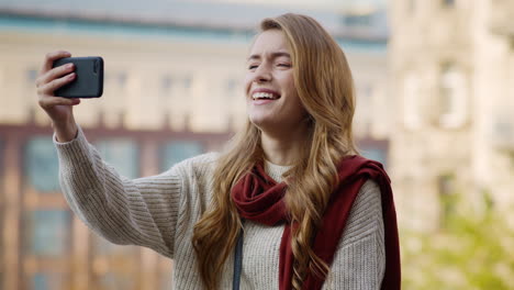 Niña-Feliz-Haciendo-Caras-Con-El-Teléfono-Al-Aire-Libre.-Mujer-Riendo-Sosteniendo-El-Teléfono-Celular.