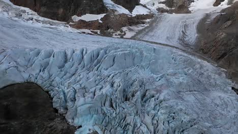 slow shot tilting up, revealing more of the glacier next to the rocky cliff