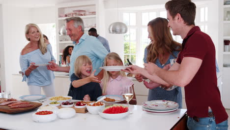 slow motion shot of multi-generation family and friends gathering in kitchen for celebration party