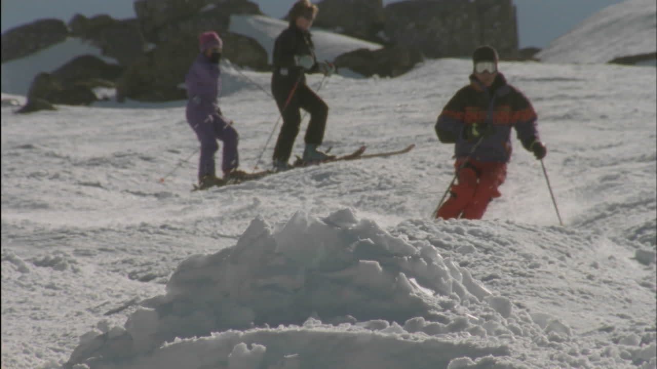 tres personas están esquiando uno salta sobre un montículo de nieve