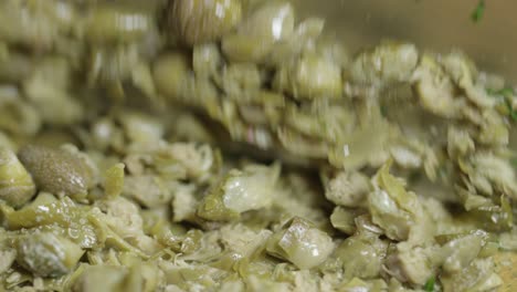 close-up of chopping capers with a knife on a cutting board