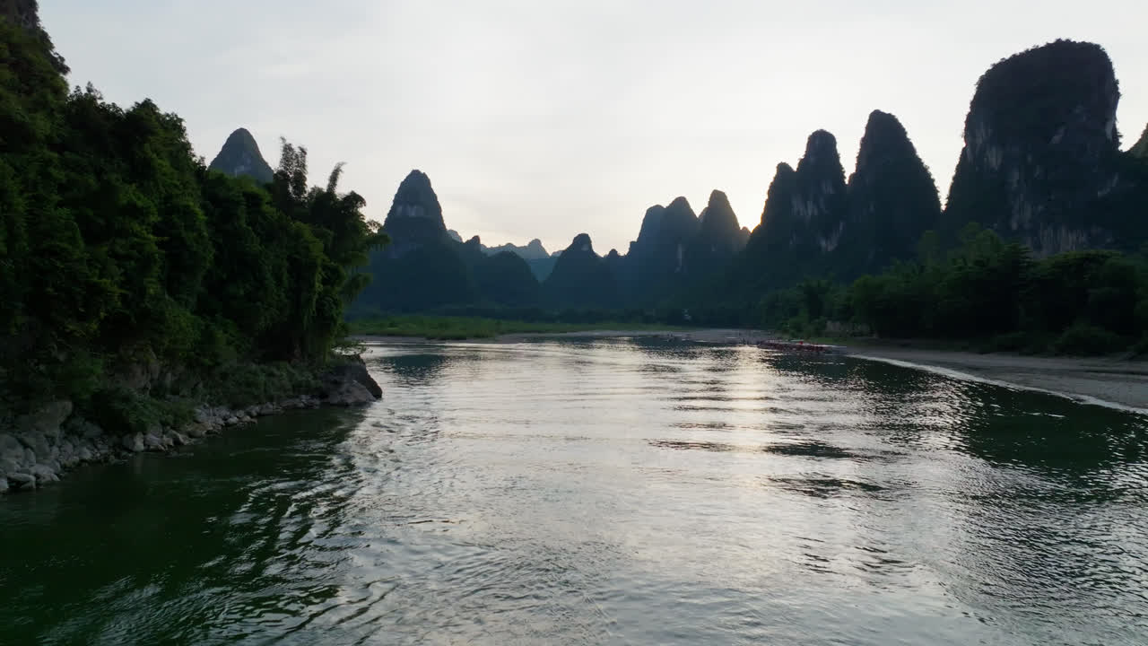 Drone flying over the Li river, revealing a riverboat, sunset in Xingping, China