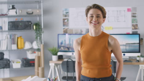 Portrait-Of-Smiling-Female-Architect-In-Office-Standing-By-Desk